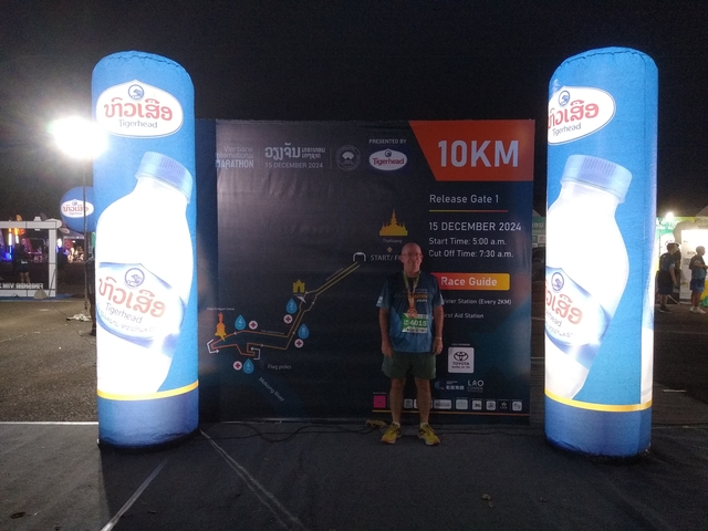       Man standing in front of a large sign at a nighttime event.
  
