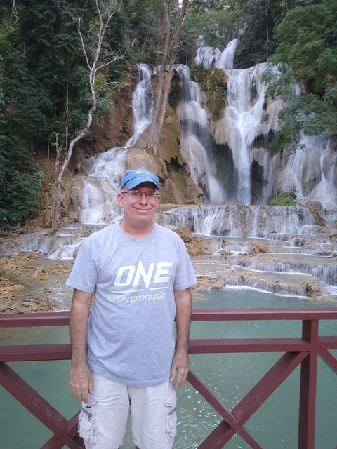       Man posing in front of a waterfall.
  