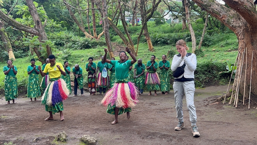 People dancing with cultural attire in a forest setting.