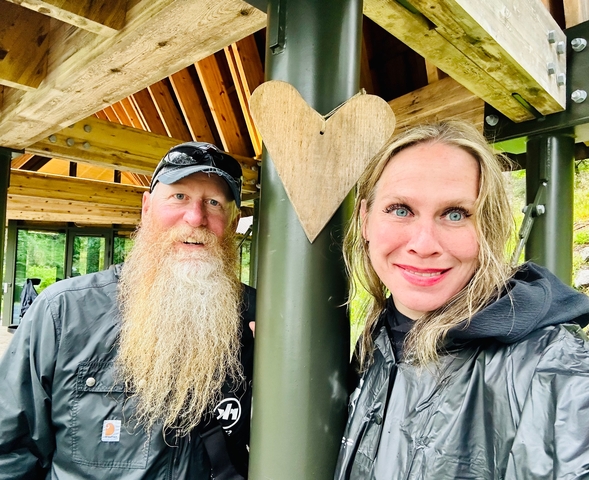 Smiling couple in a rustic setting with a heart symbol.