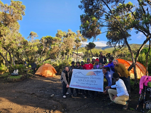       Group of people in a campsite with tents and a banner.
  