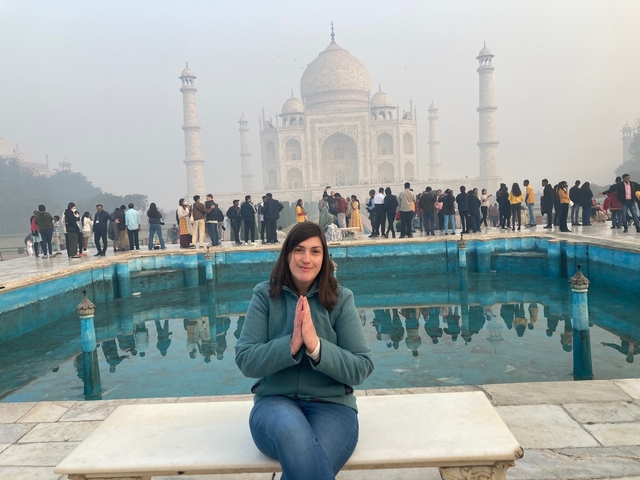 Person sitting in front of the Taj Mahal with reflection in the pool.