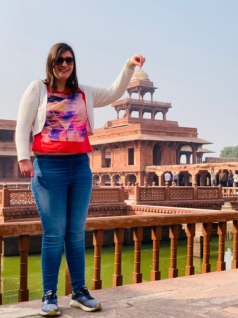 Partial view of a person in front of a red historic building.