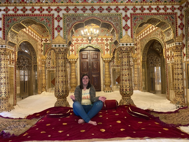 Person sitting inside a lavishly decorated room with intricate designs.