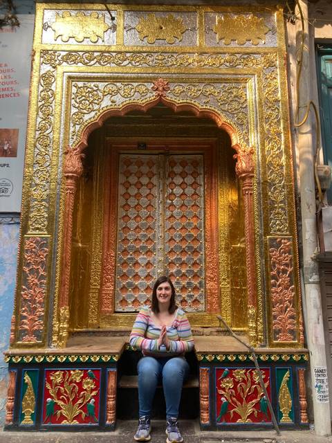 Person sitting in front of a golden ornate door.