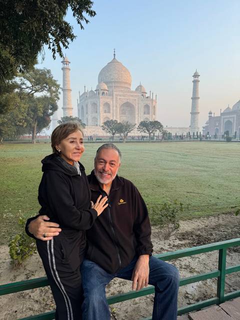       Couple posing with the Taj Mahal in the background.
  