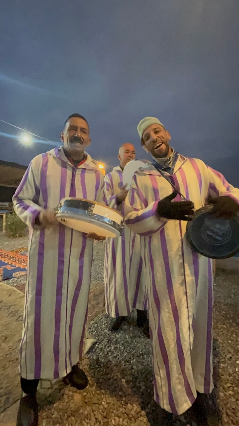 Three people wearing traditional clothes playing musical instruments.