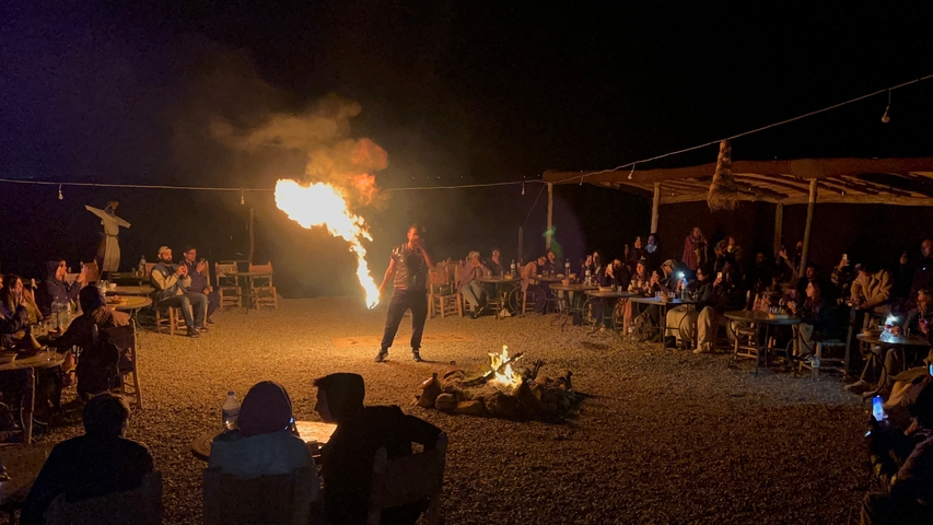       A night scene with a fire performer entertaining a group of people.
  