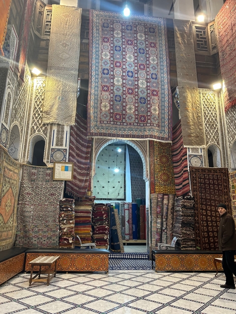       Interior of a shop with colorful hanging rugs.
  