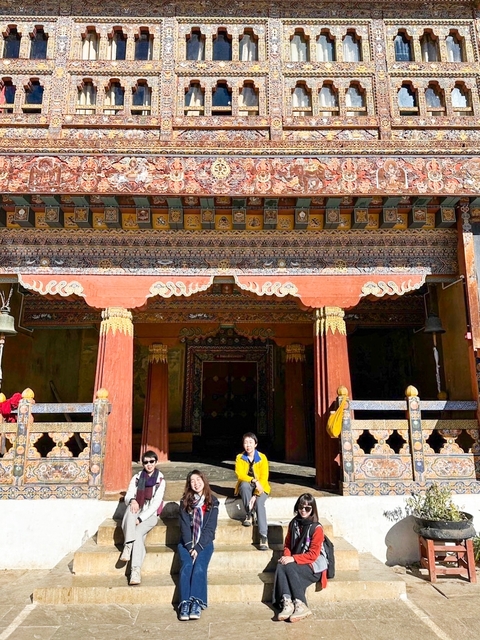A decorative entrance of a Bhutanese structure with intricate designs and people visible.