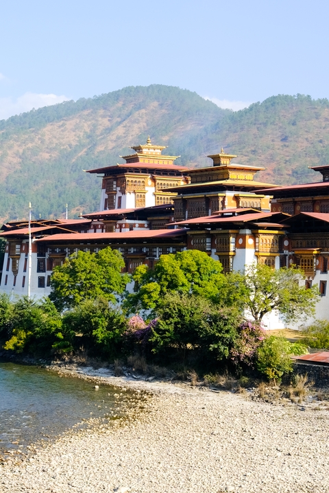 A large Bhutanese fortress-style building surrounded by greenery.