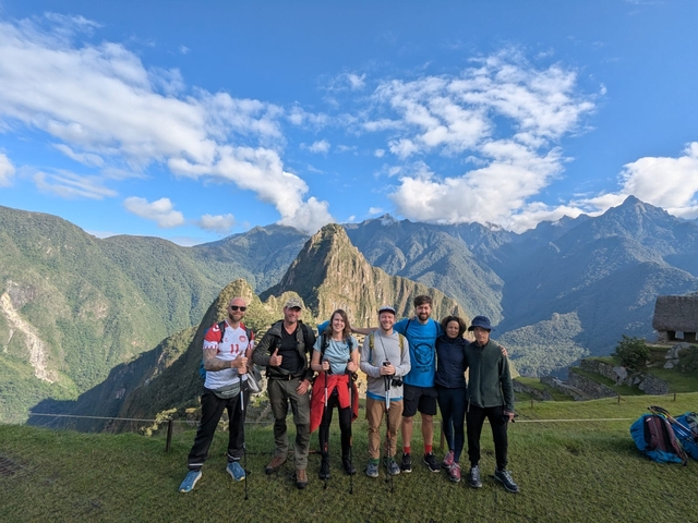 Group of hikers posing with Machu Picchu and mountains in the background.