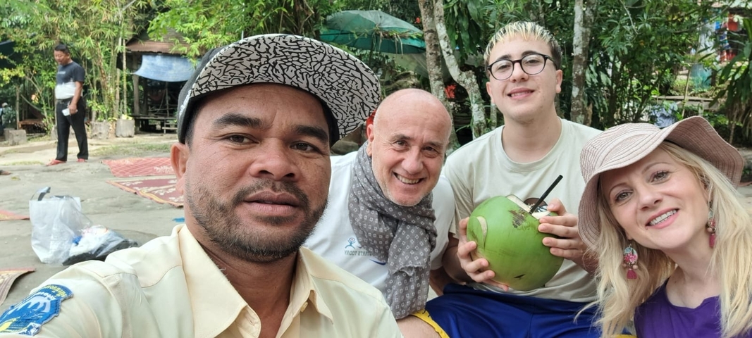       Group of people with a coconut in a natural setting.
  