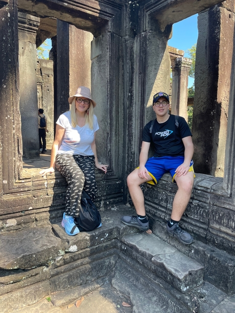      Two people sitting in an ancient stone hallway.
  