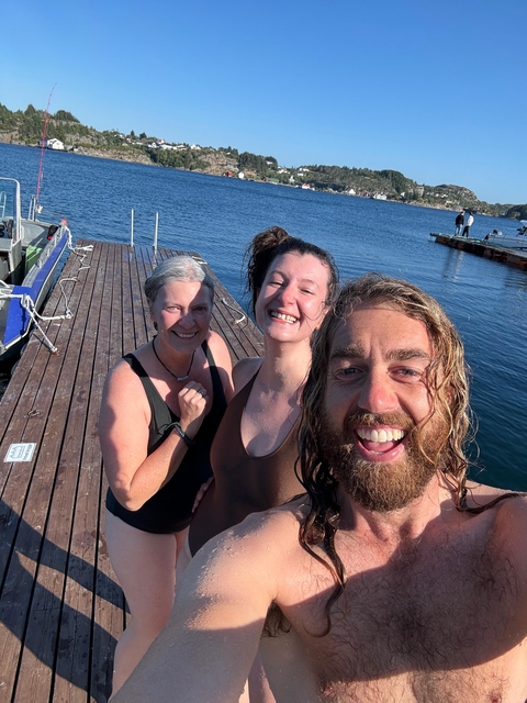       Three people smiling on a dock by the water.
  