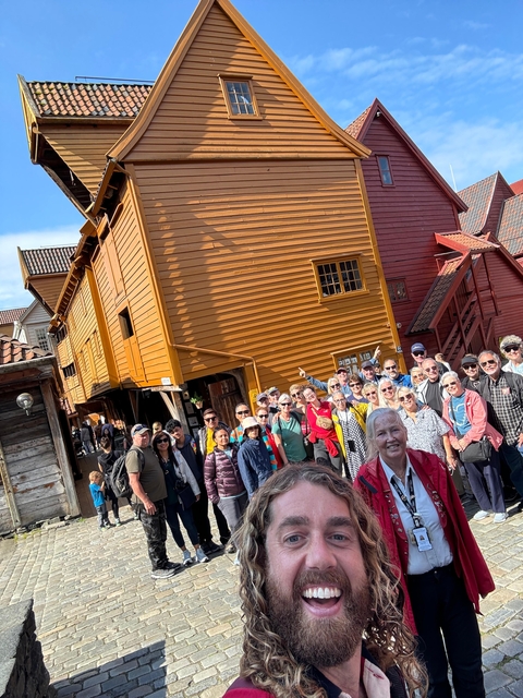       Group of people in front of wooden, historic-looking buildings.
  