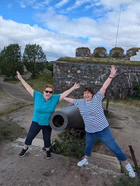       Two people posing excitedly next to a historic cannon.
  