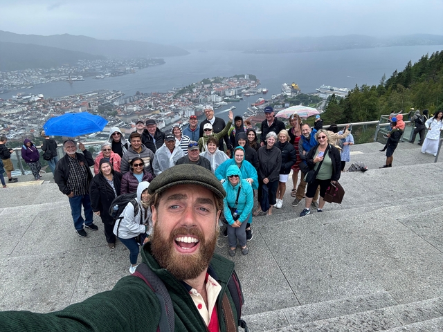       Group of people with a panoramic view of a city and the sea.
  
