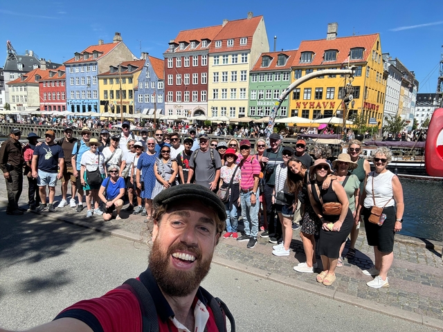      Group of people in front of colorful buildings by a canal.
  