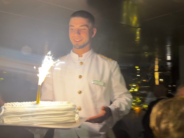 Man holding a cake with a sparkler.