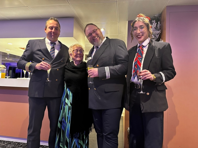 Group of people dressed formally holding glasses on a ship.