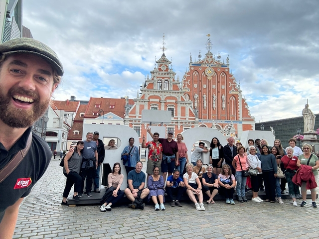 Large group of people posing in front of a historic building.