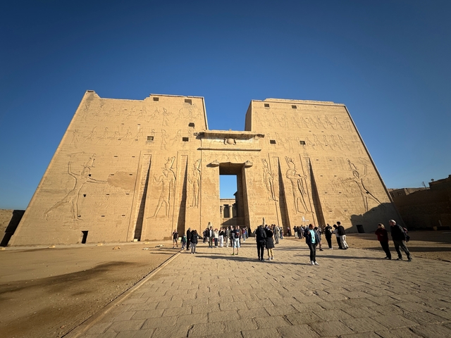       Tourists walking towards the grand entrance of an ancient temple.
  