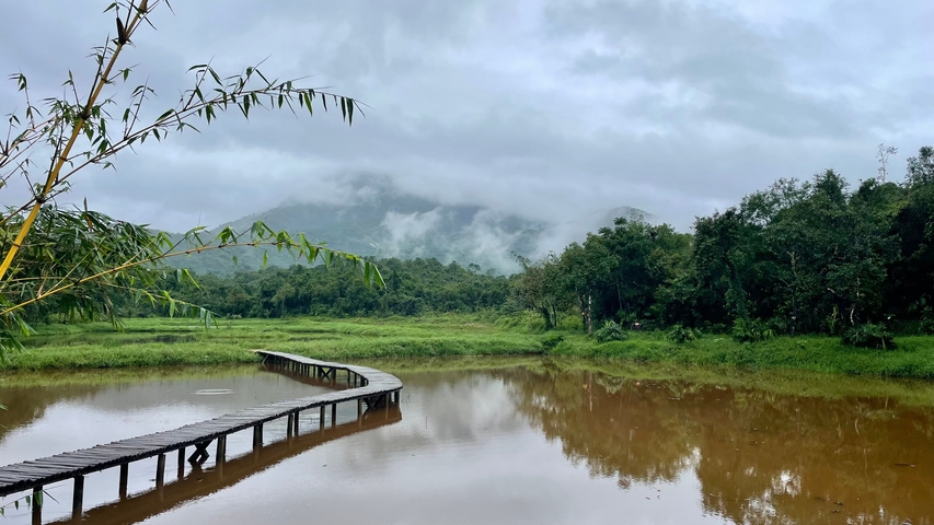 Scenic landscape with a wooden path over water and mountains in the background.