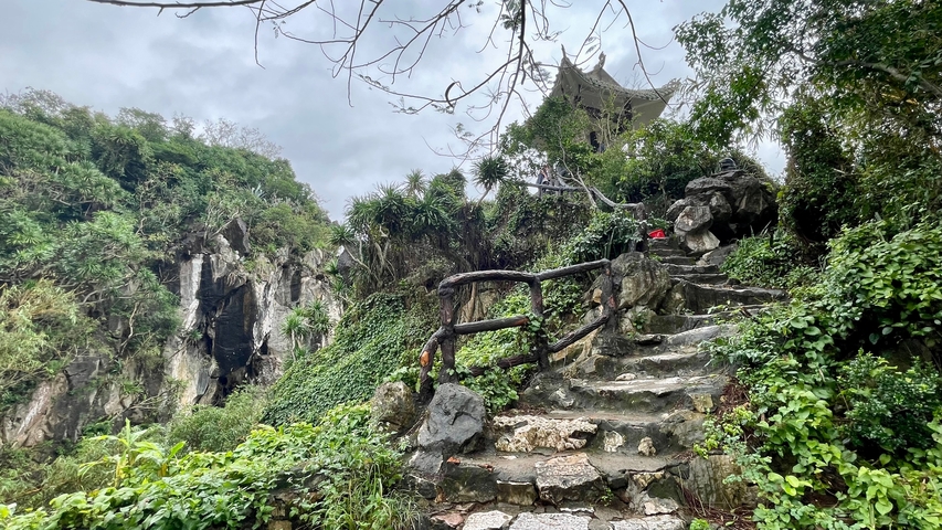Scenic landscape with stone steps leading to a temple on a hill.