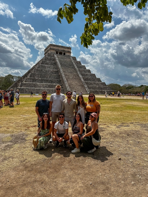 Group of tourists posing in front of Chichen Itza.