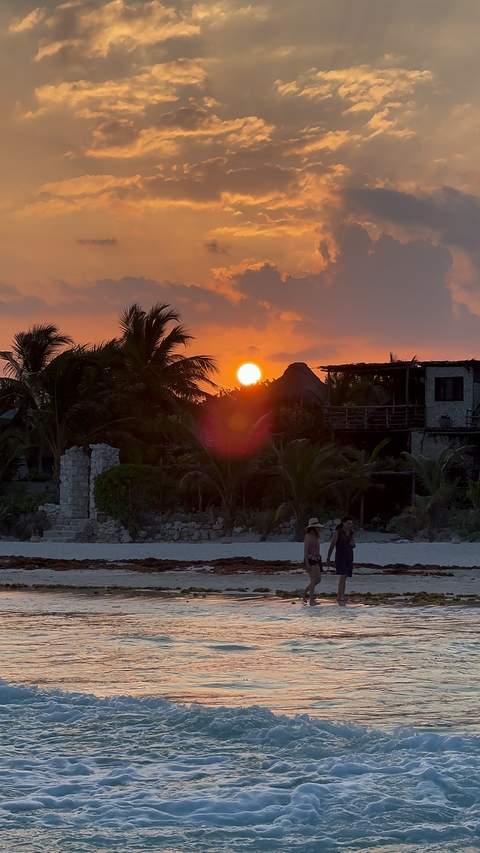 Sunset on a beach with people in the foreground.