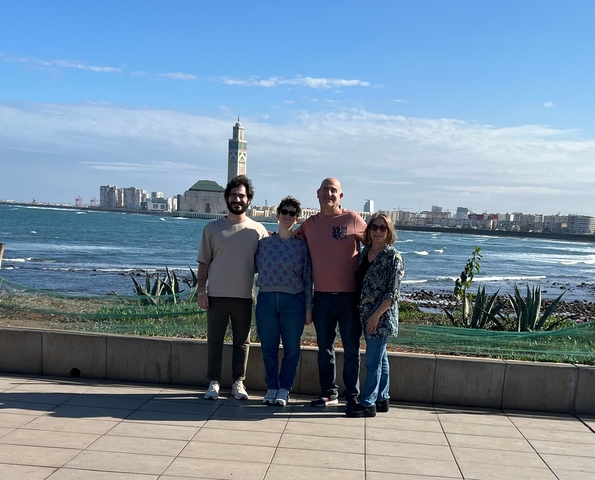 Family posing in front of a large mosque by the sea.