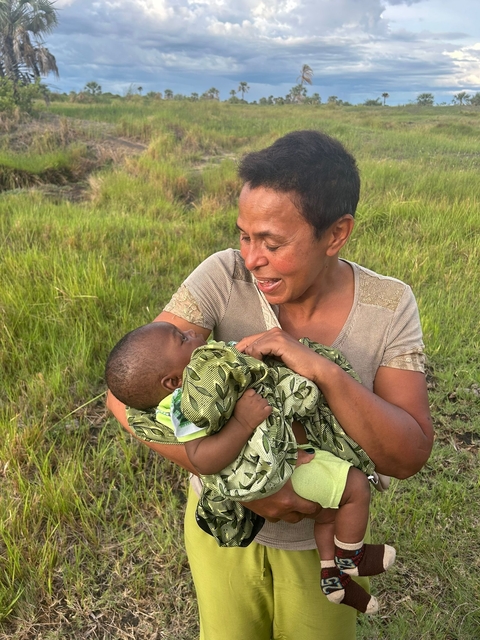       Woman holding a baby and smiling.
  