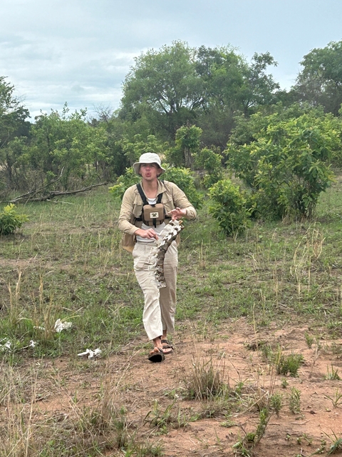       Person holding an animal bone in a grassy area.
  