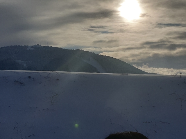       Snowy hill landscape with a cloudy sky.
  