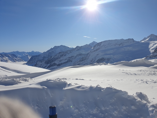       Snowy landscape with mountains and clear blue skies.
  