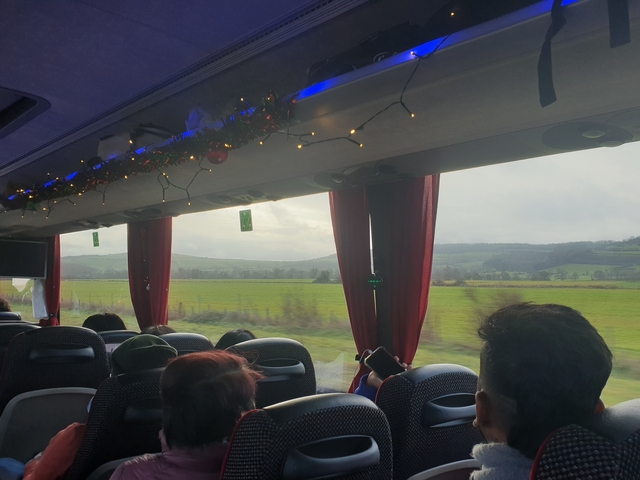       Inside view of a bus, decorated with lights, looking out at fields.
  