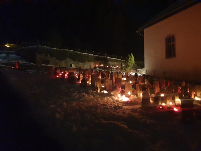       Nighttime scene of rows of lit candles in a snowy area.
  