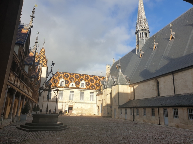       Courtyard of a historic building with patterned roof tiles.
  