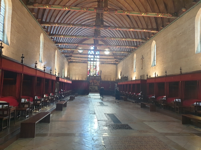       Interior hall with stained glass windows and wooden beams.
  