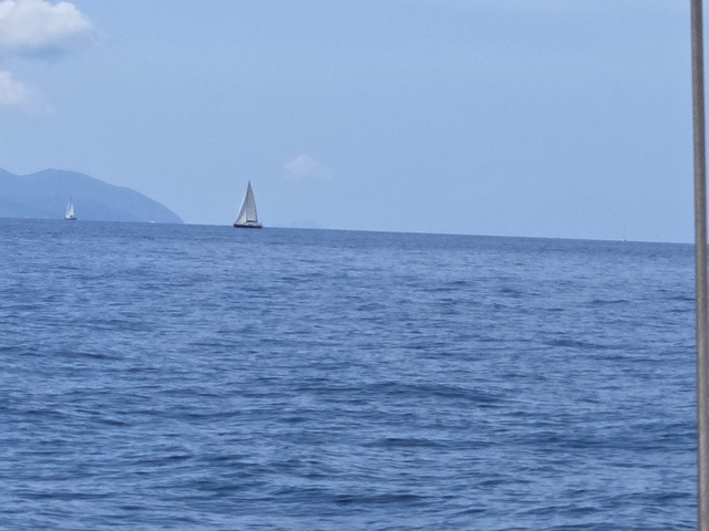 Sailboats in the distance on a calm sea.
