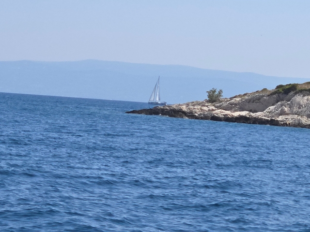 Sailboat near a rocky coastline.