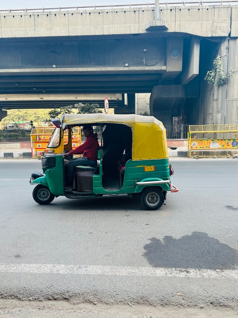       A man driving a rickshaw on a busy street.
  