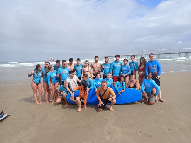 Group of people on a beach with surfboards.