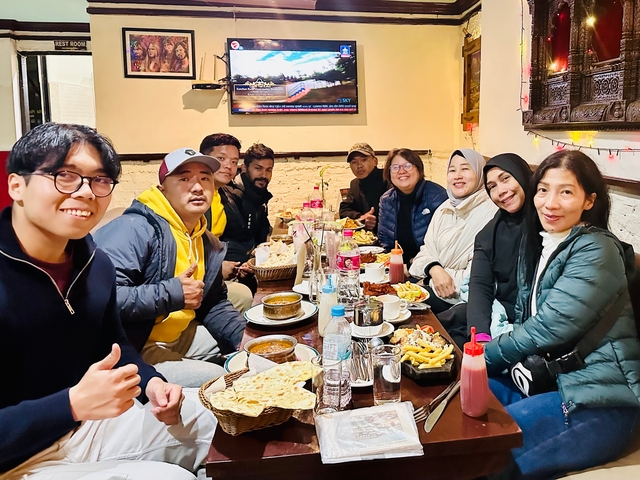       A group of people sitting around a table enjoying a meal indoors.
  
