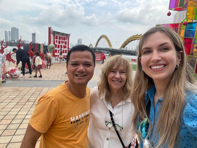 Group of people posing in front of a river with a modern bridge.