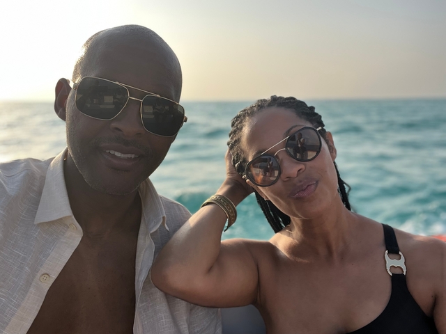       Couple posing on a boat with the sea in the background.
  