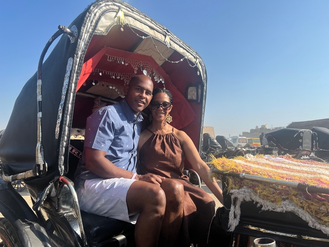      Couple sitting in a horse carriage in desert setting.
  