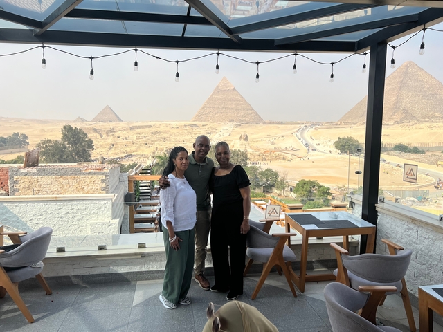       Group posing on a rooftop with views of the Pyramids.
  