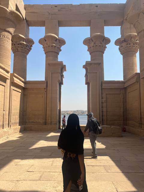       Person walking between ancient columns with a view of the water.
  